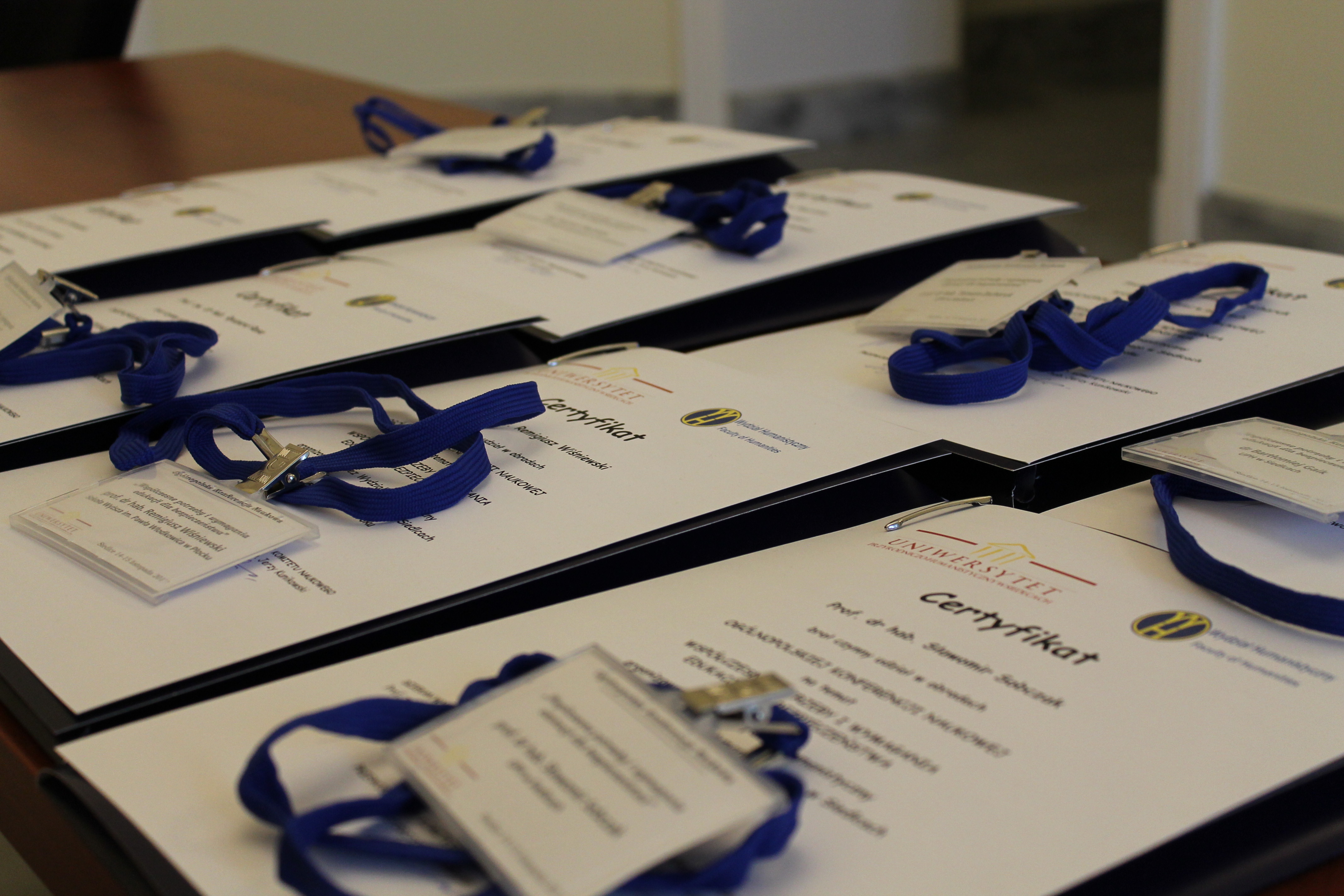 Certyfikaty uczestników wraz z identyfikatorami leżące na blacie stołu